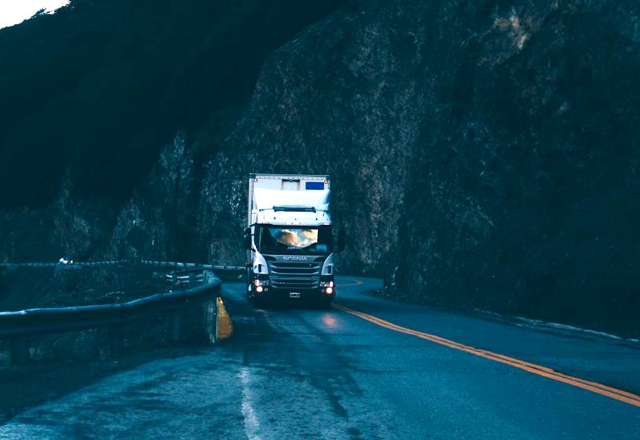 Poids lourd en approche sur une route de transit, phares allumés.